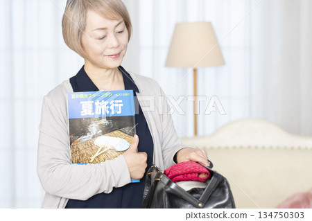 老婦人在客廳收拾行李準備旅行 134750303