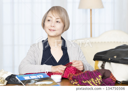 Senior woman packing for a trip in the living room Senior woman packing for a trip in the living room 134750306