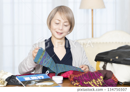Senior woman packing for a trip in the living room 134750307