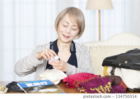 Senior woman packing for a trip in the living room 134750314