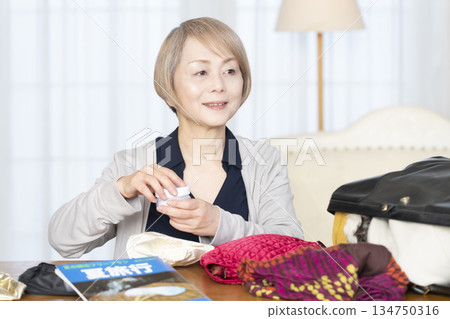Senior woman packing for a trip in the living room 134750316