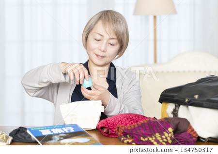 老婦人在客廳收拾行李準備旅行 134750317