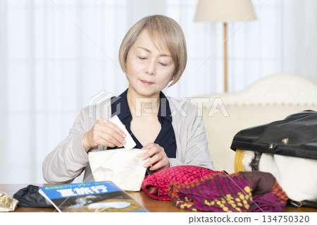 Senior woman packing for a trip in the living room 134750320