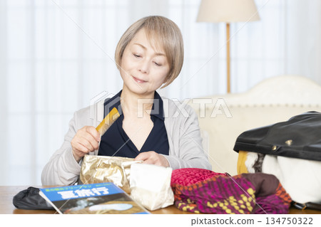 Senior woman packing for a trip in the living room 134750322