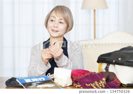 老婦人在客廳收拾行李準備旅行 134750326