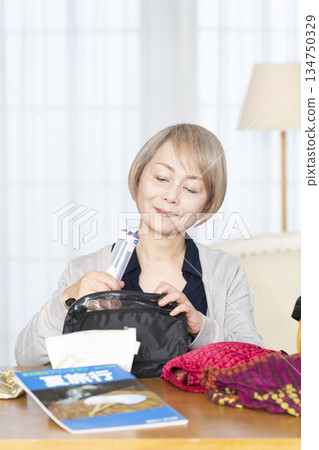 Senior woman packing for a trip in the living room 134750329
