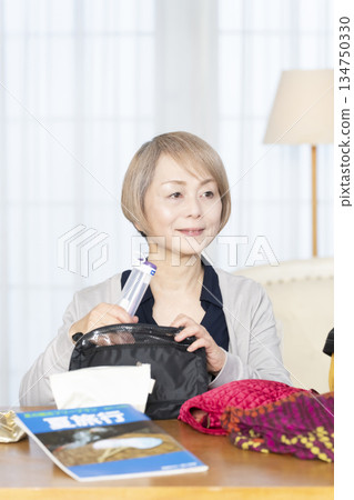 老婦人在客廳收拾行李準備旅行 老婦人在客廳收拾行李準備旅行 134750330