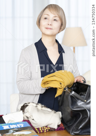Senior woman packing for a trip in the living room 134750334