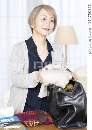 老婦人在客廳收拾行李準備旅行 134750336