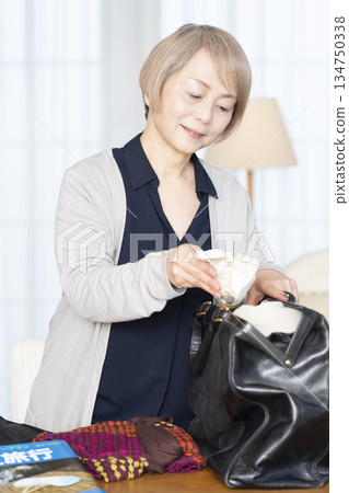 老婦人在客廳收拾行李準備旅行 134750338