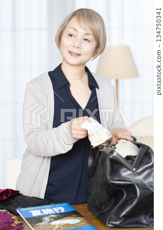 Senior woman packing for a trip in the living room 134750341