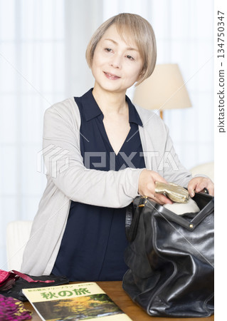 Senior woman packing for a trip in the living room 134750347