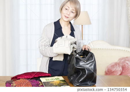老婦人在客廳收拾行李準備旅行 134750354