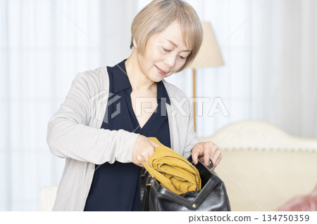 Senior woman packing for a trip in the living room 134750359