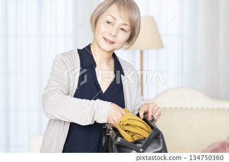 老婦人在客廳收拾行李準備旅行 134750360