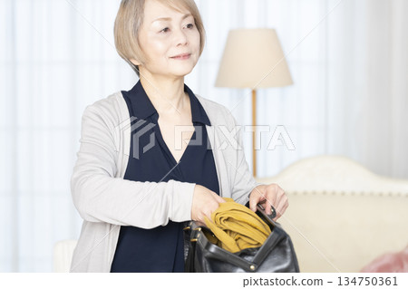 老婦人在客廳收拾行李準備旅行 134750361