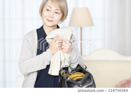 Senior woman packing for a trip in the living room 134750364