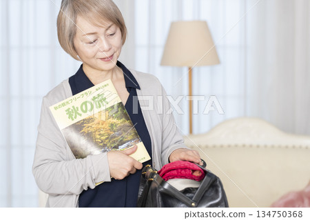 老婦人在客廳收拾行李準備旅行 134750368