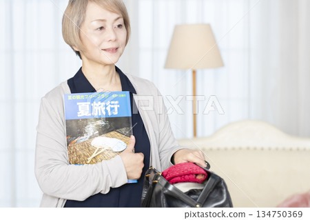 老婦人在客廳收拾行李準備旅行 134750369