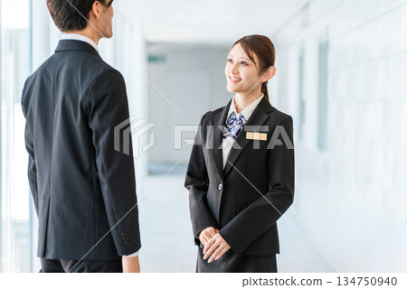 Young Asian businessmen in suits having a conversation in an office corridor Young Asian businessmen in suits having a conversation in an office corridor 134750940