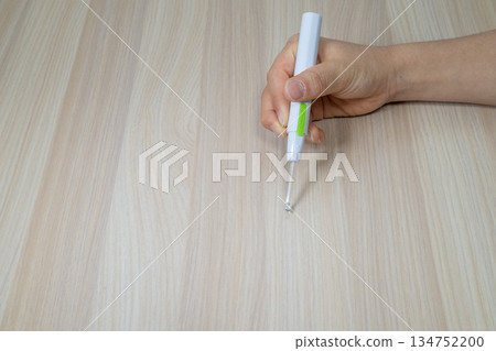 Human hand holding a lighted earpick and wood grain background Human hand holding a lighted earpick and wood grain background 134752200
