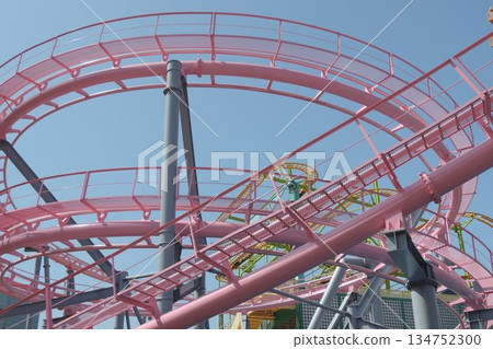 Pink roller coaster rails at an amusement park shining against the blue sky 134752300