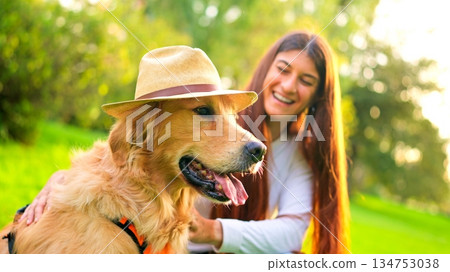 Golden retriever dog wearing hat with woman having fun 134753038