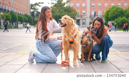 Women showing affection to pet dogs in city Women showing affection to pet dogs in city 134753040