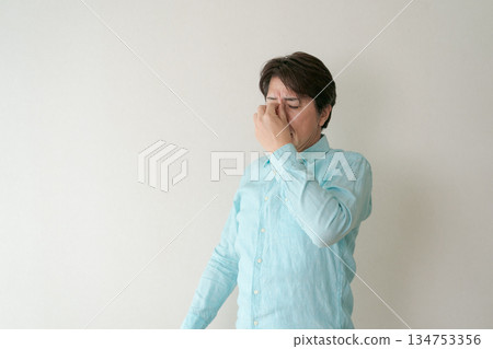 A man holding his eyes 134753356