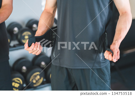 A man with back pain wearing a corset at the gym 134753518