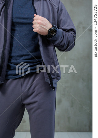 A man is wearing a stylish black watch and a fashionable grey jacket A man is wearing a stylish black watch and a fashionable grey jacket 134753729