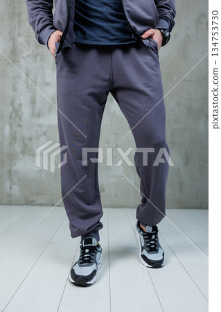 A man in a jacket and sweatpants stands on a white floor A man in a jacket and sweatpants stands on a white floor 134753730