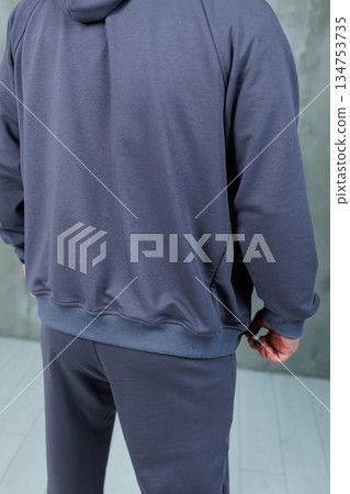 The rear view of an individual dressed in a cozy hoodie and sweatpants The rear view of an individual dressed in a cozy hoodie and sweatpants 134753735