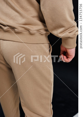 The backside view of an individual dressed in a tan sweatshirt and beige pants 134753756