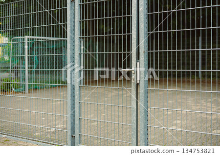 An Industrial Metal Fence Gate, situated in a bustling Urban Setting, serves as a Secure Barrier, featuring a dependable Lock Mechanism that ensures optimal safety and protection against intruders An Industrial Metal Fence Gate, situated in a bustling Urban Setting, serves as a Secure Barrier, featuring a dependable Lock Mechanism that ensures optimal safety and protection against intruders 134753821