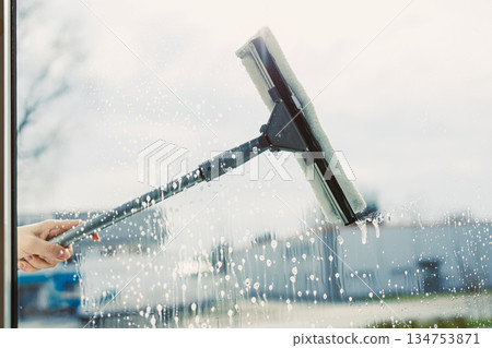 Professional Window Cleaning A Modern Technique with a Squeegee on a Bright Day 134753871