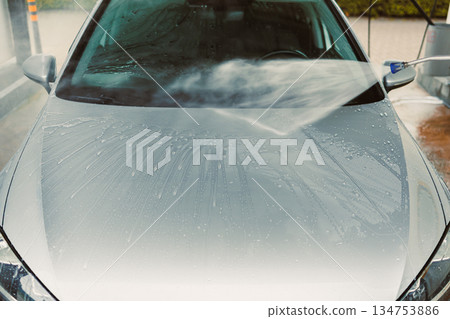 Washing a Silver Car at a SelfService Car Wash Station Under Bright Sunlight with Attention to Detail and Emphasis on Hygiene for a Fantastic Shine on the Windshield and Bodywork of the Vehicle 134753886
