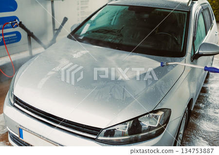 A Clean Start A shiny silver car is being meticulously washed at a selfservice car wash station, utilizing a powerful highpressure water jet to remove dirt and grime effectively from its surface A Clean Start A shiny silver car is being meticulously washed at a selfservice car wash station, utilizing a powerful highpressure water jet to remove dirt and grime effectively from its surface 134753887