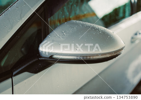 A CloseUp of a Stylish Car Side Mirror with Water Droplets Showcasing a Glossy Reflection that Exemplifies Modern Automotive Design and Craftsmanship, Capturing Every Elegant Detail A CloseUp of a Stylish Car Side Mirror with Water Droplets Showcasing a Glossy Reflection that Exemplifies Modern Automotive Design and Craftsmanship, Capturing Every Elegant Detail 134753890