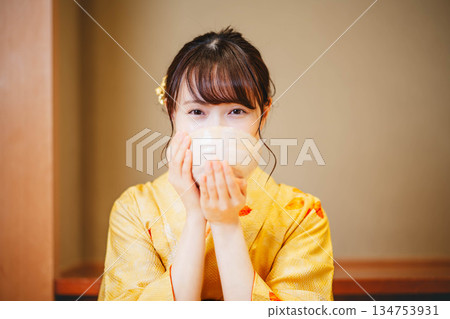 A young woman in a kimono drinking tea from a bowl 134753931