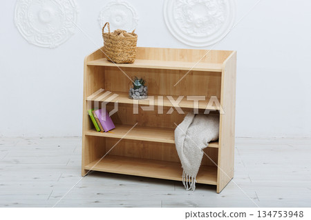 A beautifully crafted wooden shelf displaying books and a basket resting on top 134753948