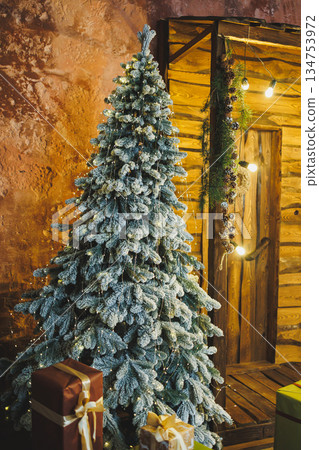 Enter a Winter Wonderland with a snowdusted Christmas tree and shimmering ornaments, surrounded by delightful gifts in a rustic setting, embodying the holiday spirit and inviting joyful celebrations 134753972