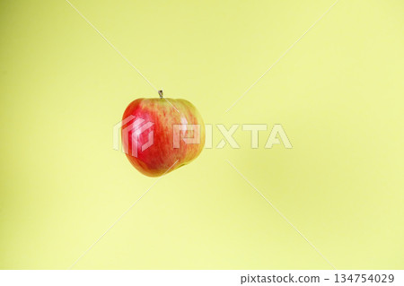 A Floating Fresh Apple Positioned on a Bright Yellow Background for a Vibrant Aesthetic 134754029