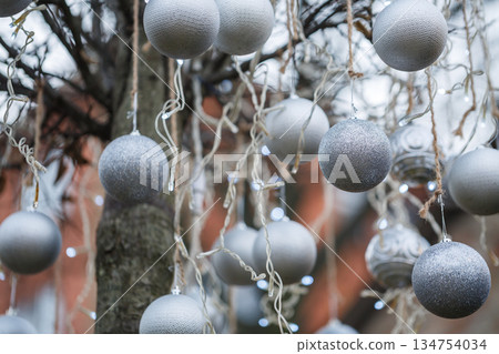 These Beautiful Silver and Gray Christmas Ornaments are delicately Hanging from a Tree, creating a truly Magical Holiday Atmosphere for everyone to enjoy during the festive season and celebrations These Beautiful Silver and Gray Christmas Ornaments are delicately Hanging from a Tree, creating a truly Magical Holiday Atmosphere for everyone to enjoy during the festive season and celebrations 134754034