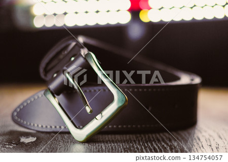 Presenting a Stylish Black Leather Belt with a Modern Buckle Design, beautifully showcased on a Wooden Surface, perfect to elevate any outfit or wardrobe essentials with an elegant touch Presenting a Stylish Black Leather Belt with a Modern Buckle Design, beautifully showcased on a Wooden Surface, perfect to elevate any outfit or wardrobe essentials with an elegant touch 134754057