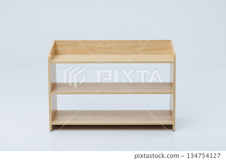A wooden shelf that has three distinct shelves against a white background A wooden shelf that has three distinct shelves against a white background 134754127
