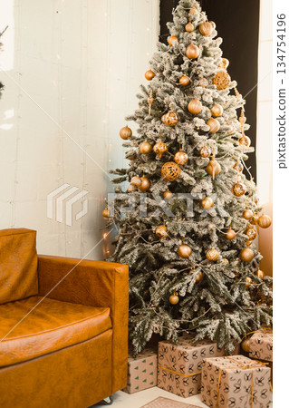 A cozy Christmas scene unfolds with a beautifully festively decorated tree, complete with shimmering ornaments and twinkling lights, alongside wrapped gifts that are ready for the holiday season 134754196