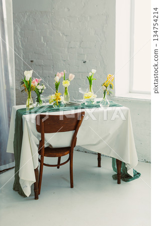 Immerse in a delightful Floral Table Setting for Spring Gatherings, featuring vibrant Fresh Blooms and a Vintage Wooden Chair, adding charm and comfort to elevate your celebration 134754214