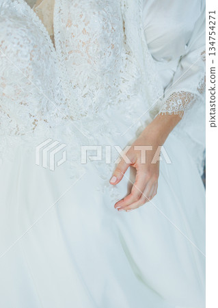 A closeup of a womans hand elegantly on a beautiful white dress 134754271