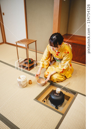 A young and beautiful kimono woman performing a tea ceremony in a Japanese-style room A young and beautiful kimono woman performing a tea ceremony in a Japanese-style room 134754326